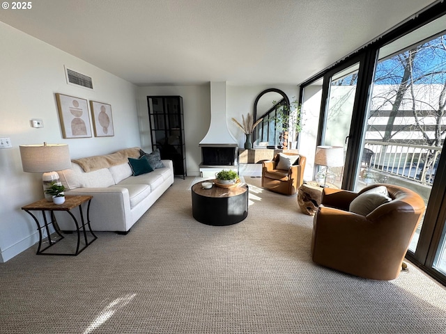 carpeted living room with a wall of windows, baseboards, and visible vents