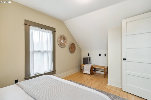 bedroom featuring vaulted ceiling, light wood-style flooring, and baseboards