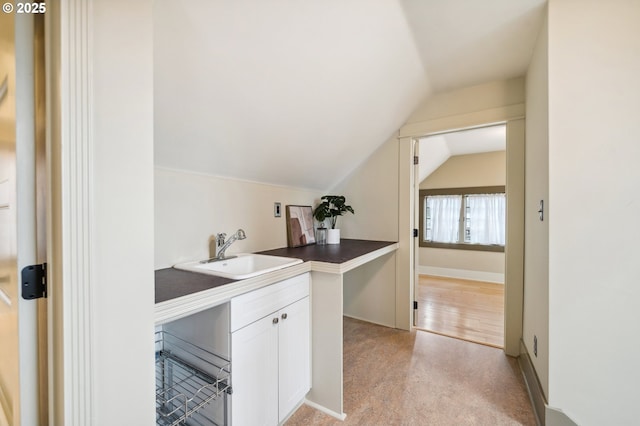 bar with vaulted ceiling, light carpet, baseboards, and a sink