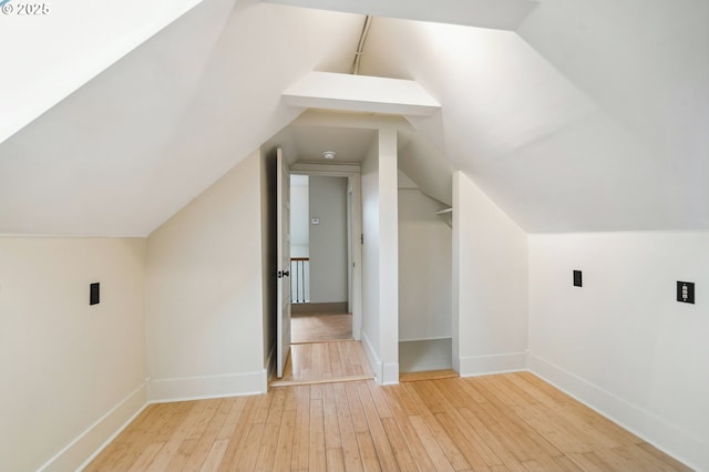 additional living space with hardwood / wood-style floors, vaulted ceiling, and baseboards