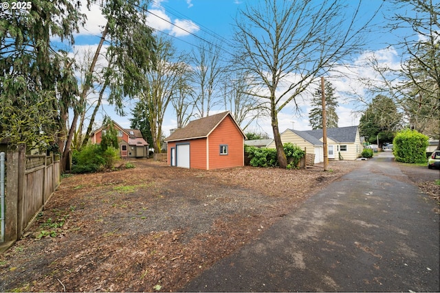 view of yard with a garage, driveway, an outdoor structure, and fence