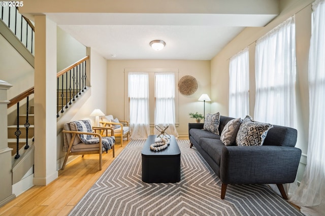 living room with stairs, baseboards, and light wood-type flooring