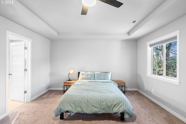 carpeted bedroom with ceiling fan, visible vents, baseboards, and a raised ceiling