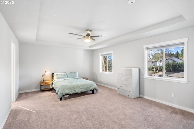 bedroom with a tray ceiling, carpet, and baseboards