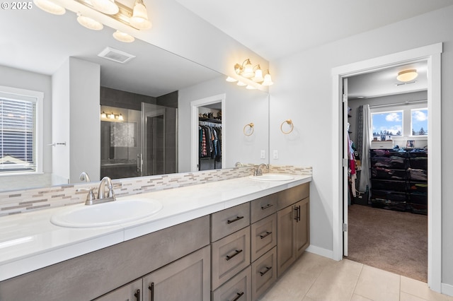 bathroom featuring a stall shower, a sink, decorative backsplash, and double vanity