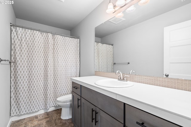 bathroom with curtained shower, stone finish floor, vanity, and toilet