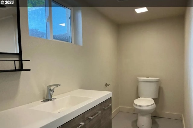 half bathroom with baseboards, toilet, and vanity