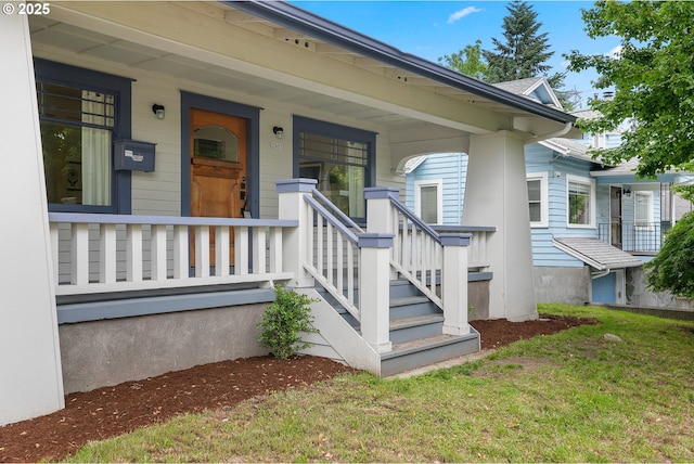 view of exterior entry featuring a porch and a lawn