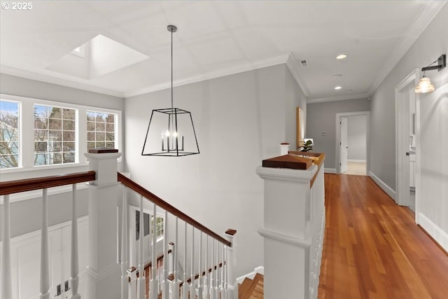 hallway with ornamental molding, a chandelier, light wood-type flooring, and a skylight