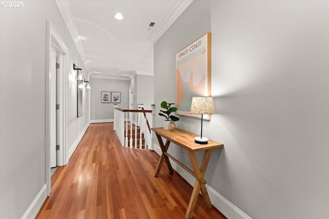 corridor with ornamental molding and light hardwood / wood-style floors