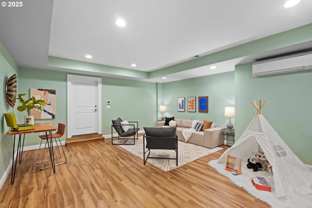 living room with hardwood / wood-style flooring, a wall mounted air conditioner, and a raised ceiling