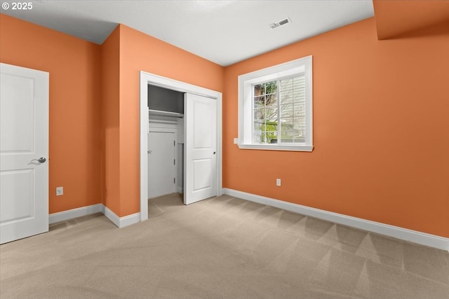 unfurnished bedroom featuring light colored carpet and a closet