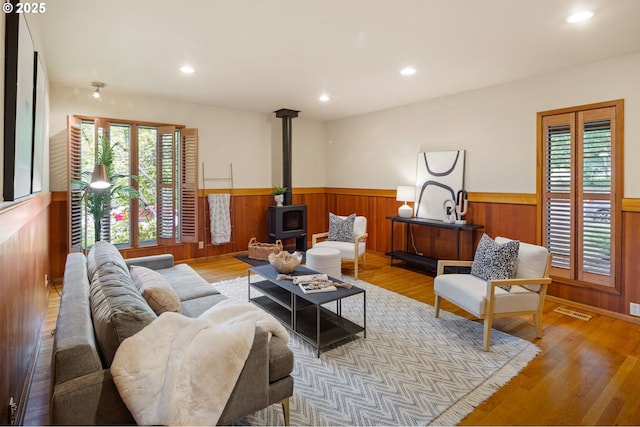 2112 Agate St, Eugene, OR 97403 - living room with a wainscoted wall, plenty of natural light, a wood stove, wood finished floors, and wooden walls