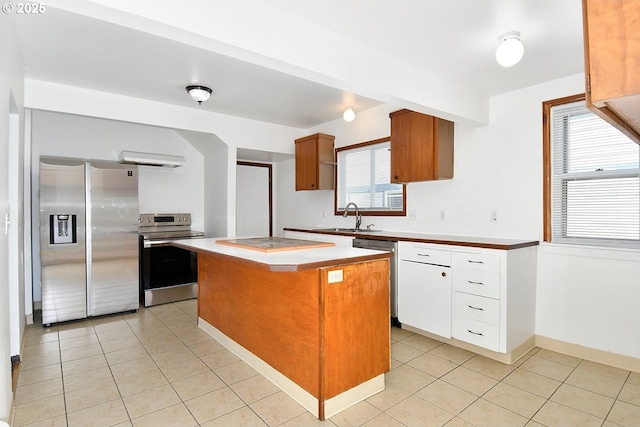 kitchen featuring light tile patterned flooring, appliances with stainless steel finishes, a center island, and a sink