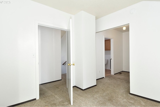 empty room featuring baseboards and light colored carpet