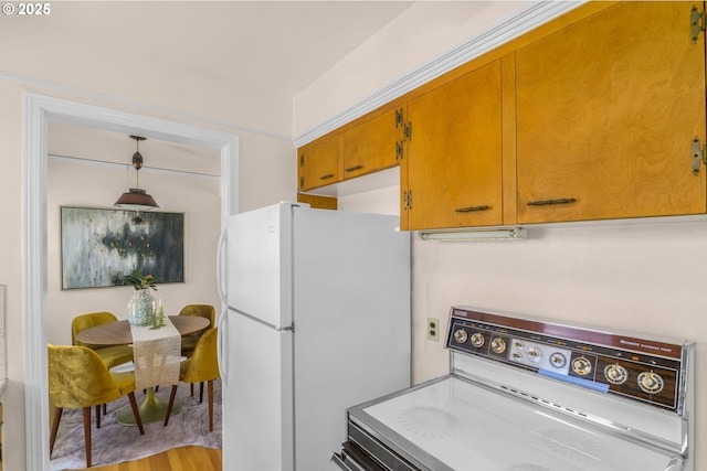 6356 N Omaha Ave, Portland, OR 97217 - kitchen with stove, freestanding refrigerator, brown cabinetry, and light wood-style floors