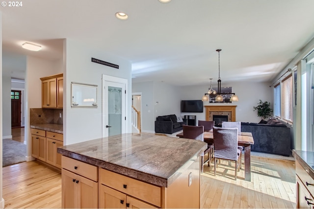 kitchen featuring light brown cabinets, backsplash, a center island, and light wood-type flooring