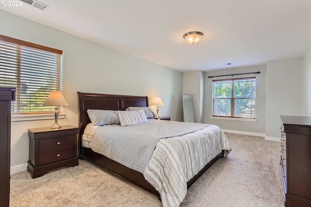 bedroom featuring light colored carpet and multiple windows