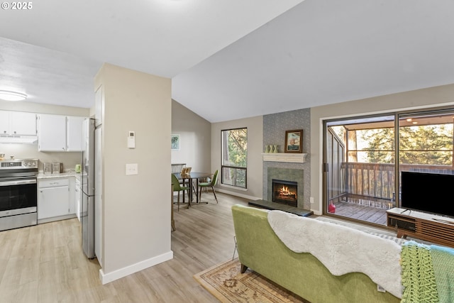 living room with a large fireplace, vaulted ceiling, and light hardwood / wood-style flooring