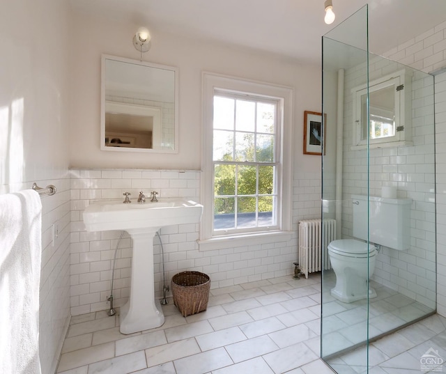 bathroom featuring tile patterned floors, toilet, radiator, and tile walls