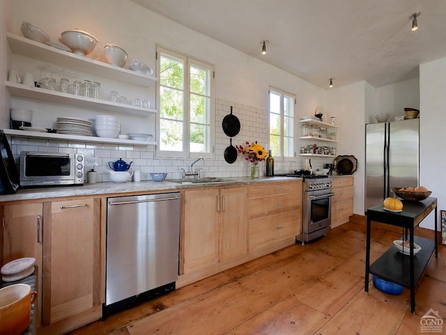 kitchen featuring sink, light hardwood / wood-style flooring, backsplash, light brown cabinetry, and appliances with stainless steel finishes