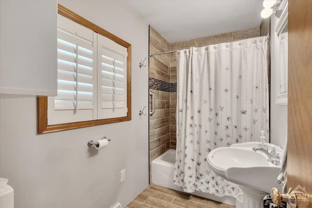 bathroom with shower / tub combo with curtain, a sink, and wood finished floors