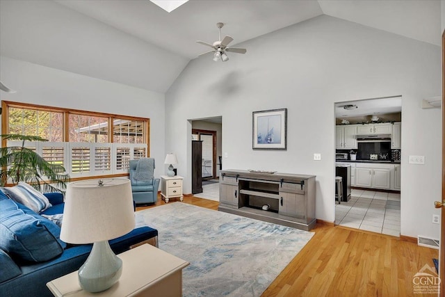 living room with ceiling fan, light wood-style flooring, high vaulted ceiling, and visible vents