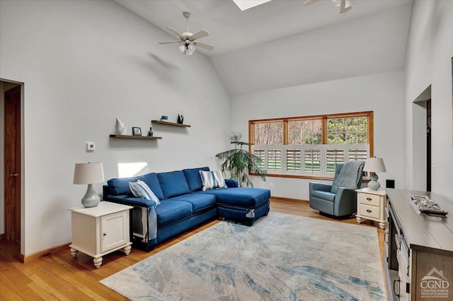 living room with baseboards, a ceiling fan, and light wood-style flooring