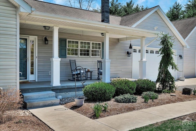 entrance to property with a porch, a shingled roof, and an attached garage