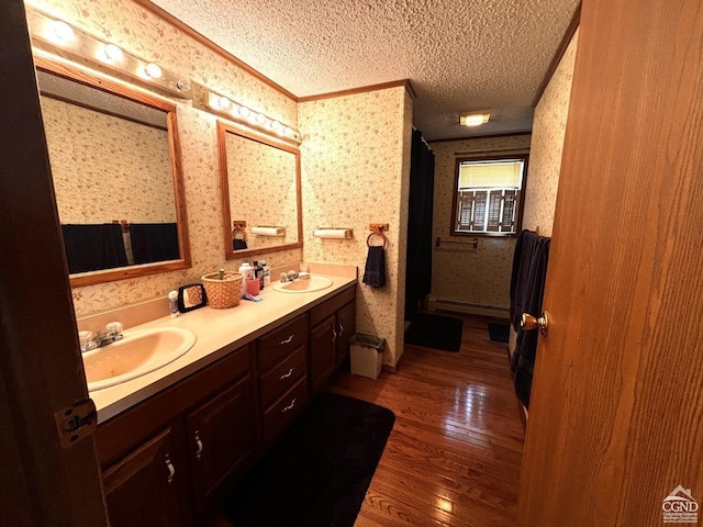 bathroom with vanity, hardwood / wood-style floors, a textured ceiling, and baseboard heating