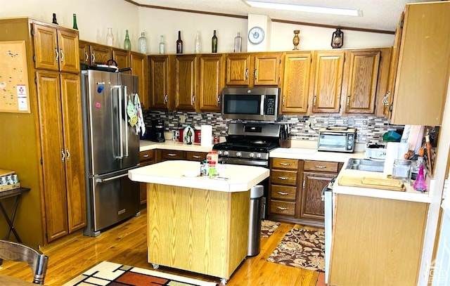 kitchen with a center island, light hardwood / wood-style flooring, vaulted ceiling, a textured ceiling, and appliances with stainless steel finishes