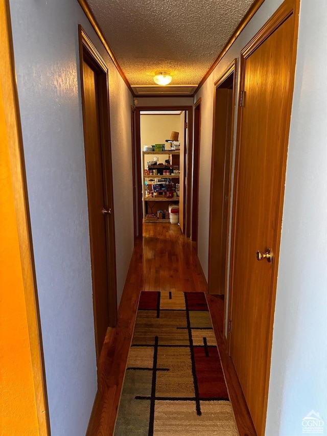 hall with a textured ceiling, dark hardwood / wood-style floors, and ornamental molding