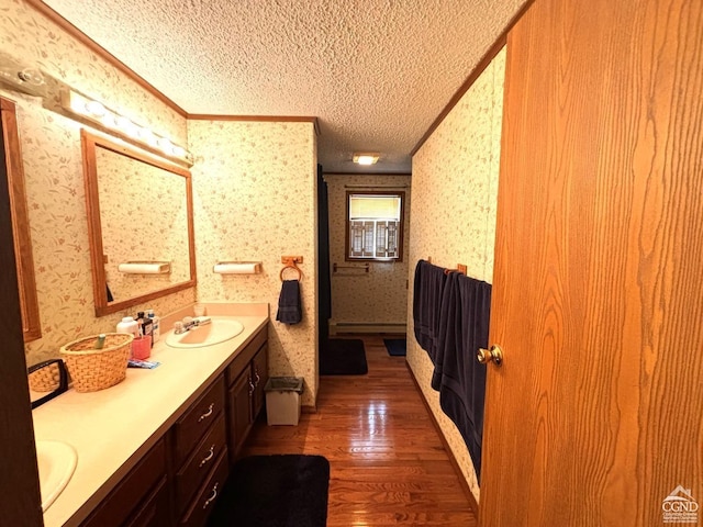 bathroom with crown molding, vanity, a textured ceiling, and hardwood / wood-style flooring