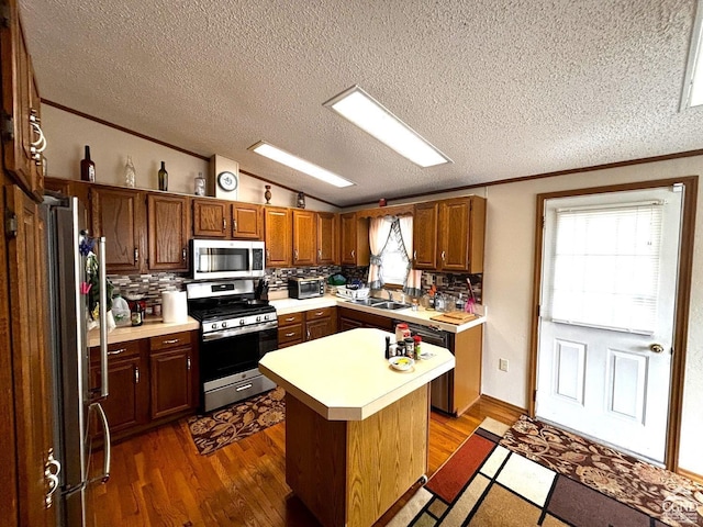 kitchen featuring appliances with stainless steel finishes, backsplash, a kitchen island, and dark wood-type flooring