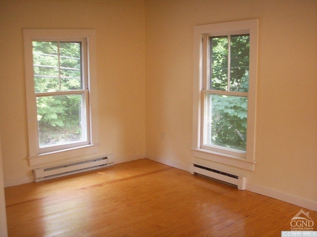 spare room featuring a baseboard heating unit and light hardwood / wood-style floors