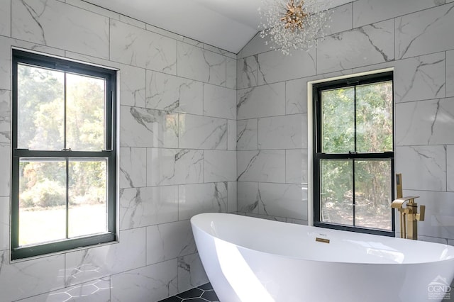 bathroom with a washtub, tile walls, and a notable chandelier