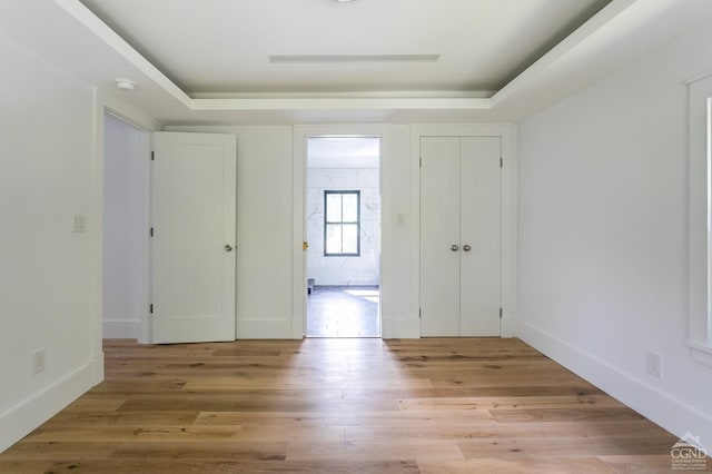 interior space with light hardwood / wood-style floors and a raised ceiling