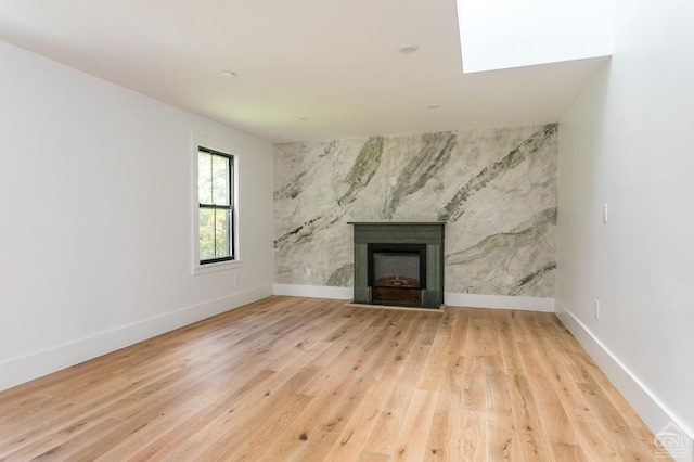 unfurnished living room featuring light wood-type flooring and a high end fireplace