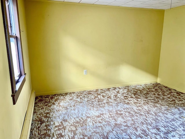 carpeted spare room featuring a drop ceiling and baseboard heating