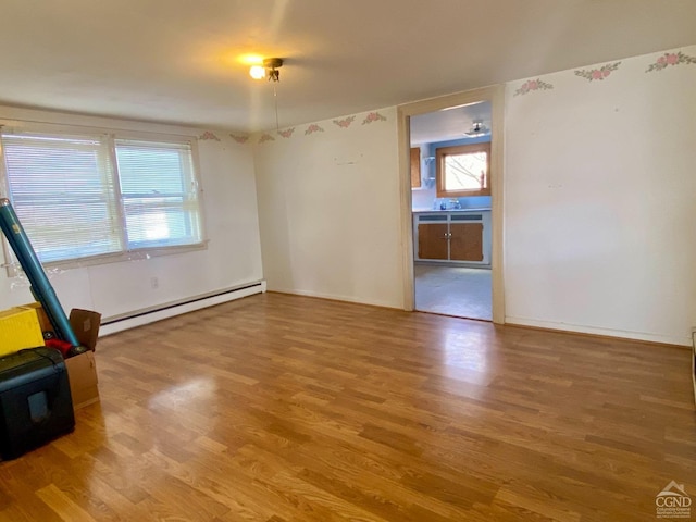 spare room featuring hardwood / wood-style floors and a baseboard heating unit