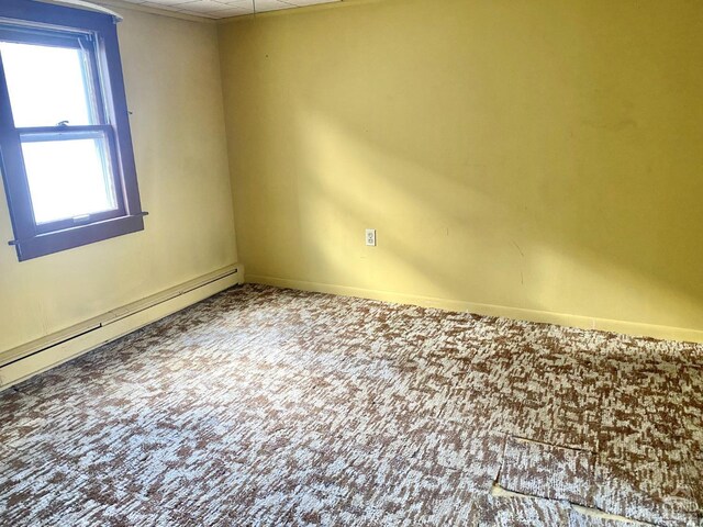 carpeted empty room with a baseboard radiator