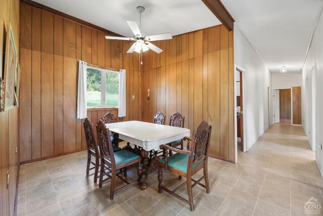 dining room featuring ceiling fan and wood walls