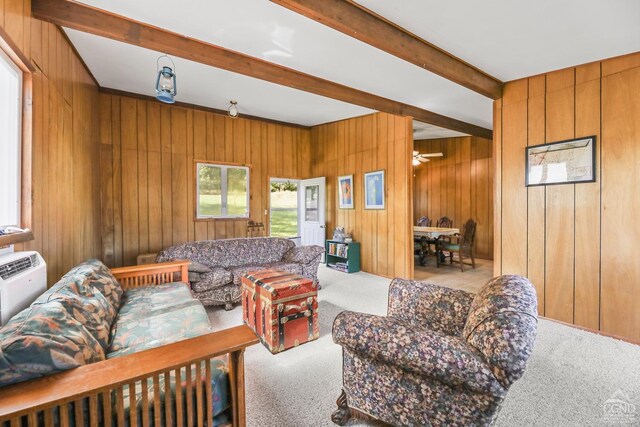 living room featuring beamed ceiling, ceiling fan, light colored carpet, and wooden walls