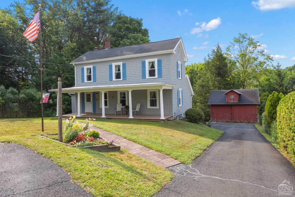 view of front facade with a storage unit, a porch, and a front yard