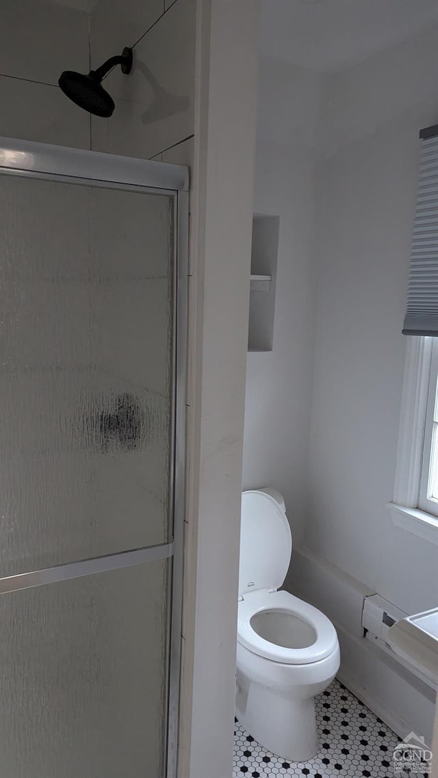 bathroom featuring a shower with shower door, tile patterned floors, and toilet