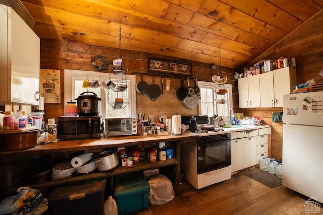 kitchen featuring gas range, wood ceiling, stainless steel microwave, hardwood / wood-style floors, and freestanding refrigerator