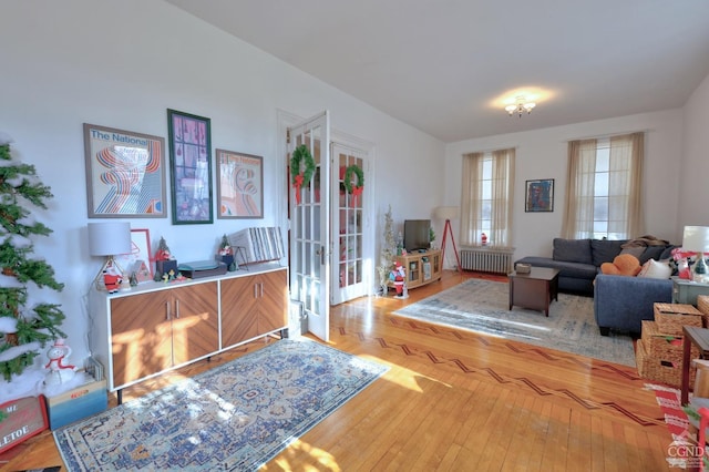 living room with radiator heating unit, light wood-type flooring, and french doors