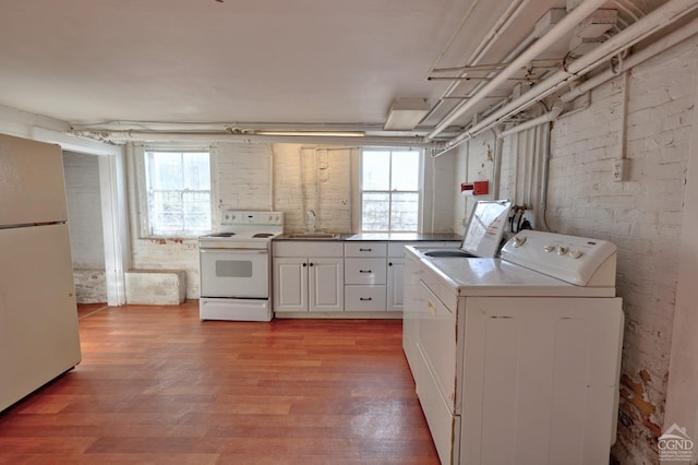 laundry room featuring washing machine and clothes dryer, a wealth of natural light, light hardwood / wood-style flooring, and sink