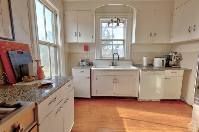 kitchen with a wealth of natural light, white cabinetry, and white dishwasher