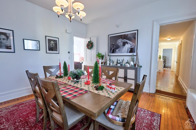 dining space featuring radiator heating unit, hardwood / wood-style flooring, and an inviting chandelier